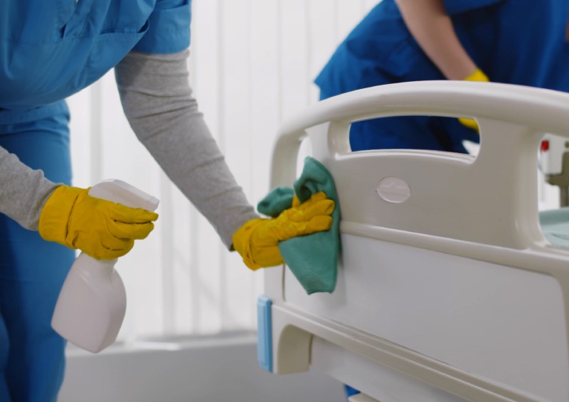 Team of professional janitors using equipment disinfecting hospital ward