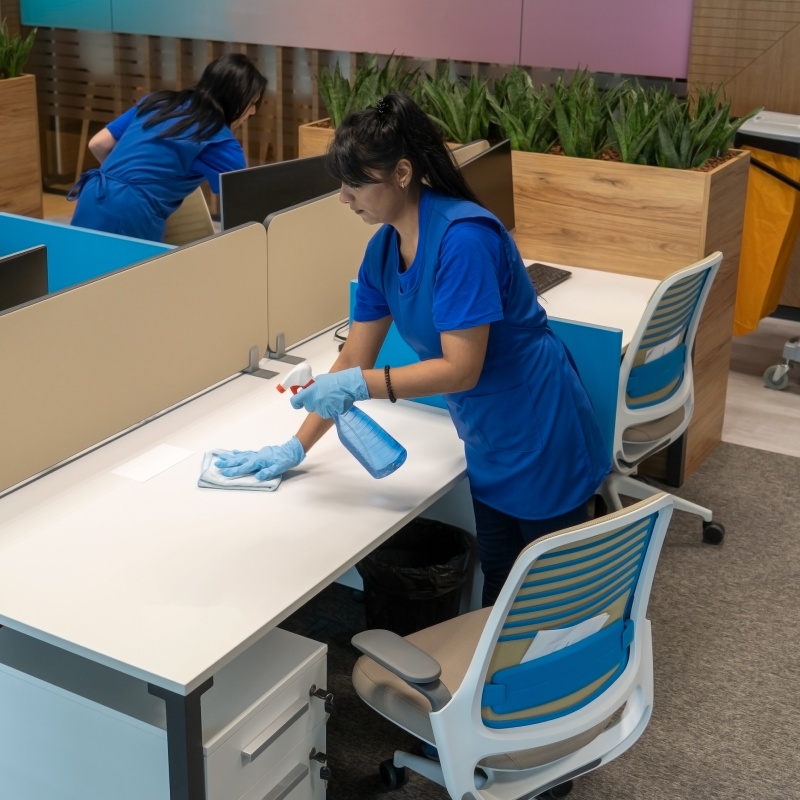 Cleaning ladies clean desks in an empty office space.Cleaning maintenance concept